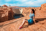 A young woman on red rocks admires the view of Glen Canyon Dam, Arizona