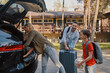 © gstockstudio - Happy young family with little packing stuff into the car and smiling while standing near house