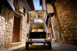 Wide Angle Rear View White Historic Vehicle With Open Trunk On Narrow Cobblestone Street In A Village