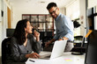 © JustLife - Colleagues in office. Businesswoman and businessman discussing work in office. Two friends working together
