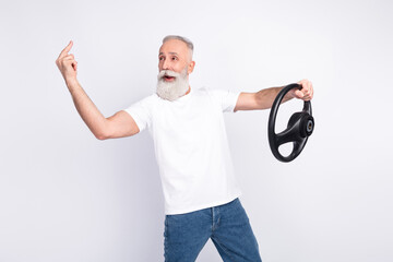Wall Mural - Portrait of attractive aggressive man holding in hands steering wheel showing middle finger isolated over light grey color background