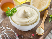Bowl With Mayonnaise Sauce In The Centre And Mayonnaise Ingredients Around It On Wooden Table. Close-up.