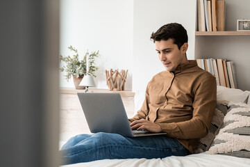 Wall Mural - Hispanic business man using laptop computer indoor in bed at home - Focus on face