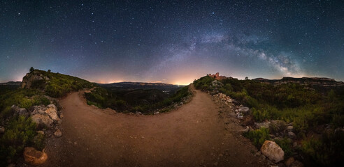 Wall Mural - Beautiful image of the arch of the Milky Way over a medieval castle. Symmetry between the Milky Way and the path that goes up to the castle. Night panoramic of the Milky Way in nature

