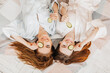 © Daria Lukoiko - Two girls make homemade face and hair beauty masks. Cucumbers for the freshness of the skin around the eyes. Women take care of youthful skin. Girlfriends laugh at home lying on the floor on pillows.