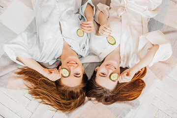 Wall Mural - two girls make homemade face and hair beauty masks. cucumbers for the freshness of the skin around t