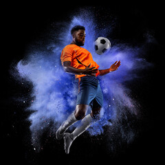 Wall Mural - One young sportsman soccer football player in explosion of colored neon powder isolated on dark background