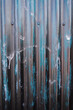 peeling black paint and white drips on a blue corrugated iron door