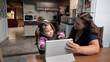 disabled child playing with mother and digital tablet in the kitchen. .