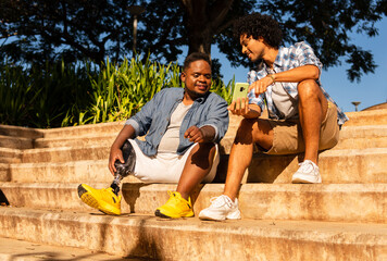 disabled black man and friend looking at cell phone screen.