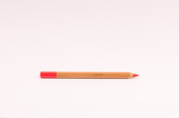 Canvas Print - Closeup of a wooden red pencil on light opink empty surface