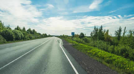 Wall Mural - The road among the Karelian taiga. Pine forest on the side of the road. Trip to Karelia. Highway among the trees. Driving on a trip to beautiful places. Karelia. Day.