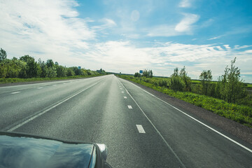 Wall Mural - The road among the Karelian taiga. Pine forest on the side of the road. Trip to Karelia. Highway among the trees. Driving on a trip to beautiful places. Karelia. Day.