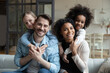 © fizkes - Portrait of happy young multiethnic family with small diverse daughters relax in living room at home. Smiling multiracial mom and dad cuddle hug with adopted small girls children. Adoption concept.
