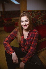 Poster - Vertical shot of a young blonde female in a black top and checkered shirt posing at home