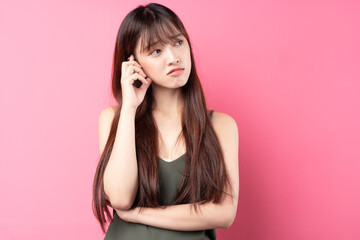 Wall Mural - Portrait of a beautiful young asian girl posing on a pink background