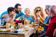 Family group celebrate and have fun together in friendship outdoor at home with a table full of food and drinks - from young boy with mother and father and parents enjoying time and party leisure