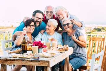 Family generations enjoy and celebrate with fun all together laughing and smiling posing for a picture outdoor at home - table full of food and drinks to eat for caucasian people