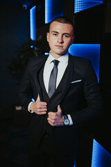 Sticker - Vertical shot of a young attractive male in a formal suit posing in a nightclub