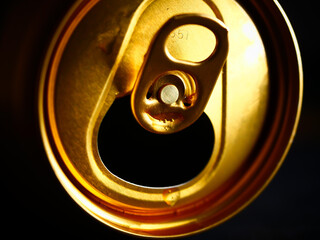 Sticker - Closeup shot of a golden empty open drink can in the dark