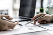 © kamiphotos - Two business partners are brainstorming on planning, managing and solving company problems, they are pointing at the company financial documents. The concept of business management for growth.
