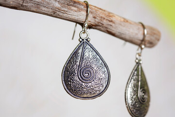 Wall Mural - Brass metal earrings in ornamental shape hanging on neutral background