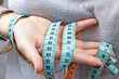 Caucasian woman hand holding the measuring tape with the 90-60-90 centimeters on it. The ideal woman figure and weightloss concept.
