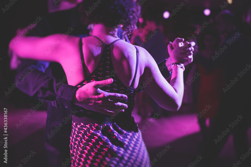 Couples dancing traditional latin argentinian dance milonga in the ballroom, tango salsa bachata kizomba lesson in the red, purple and violet lights, dance festival - obrazy, fototapety, plakaty 