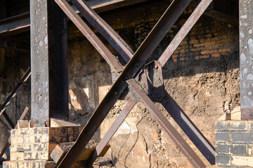 Wall Mural - Rusted metal girders in front of an old brick wall, sunshine and shadows, horizontal aspect