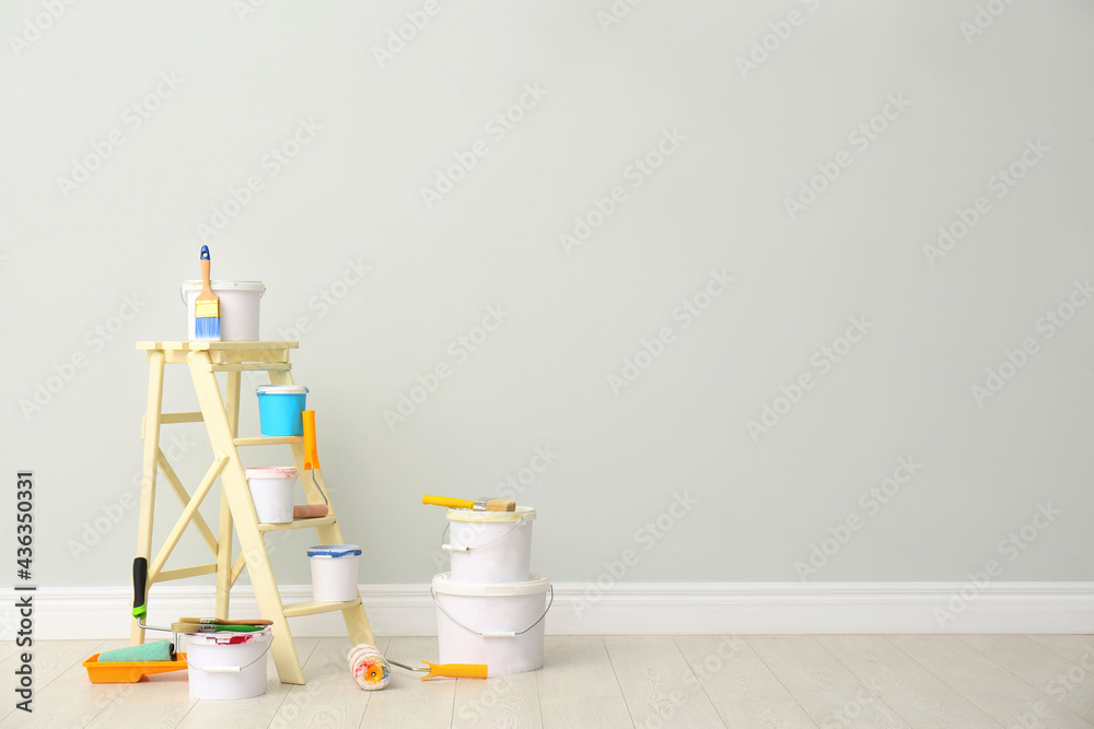 Decorator's kit of tools and paints near light wall indoors. Space for text - obrazy, fototapety, plakaty 