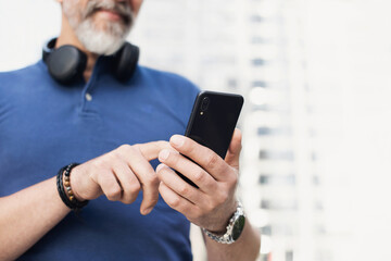 Wall Mural - Senior man using smartphone in a city. Mature middle age man looking at mobile phone. Active seniors, modern lifestyle, connection, communication, business concept