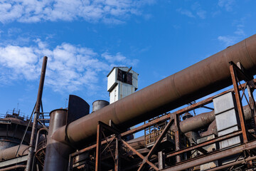 Wall Mural - Rusting metal exterior of an old industrial site against a brilliant blue sky, industrial landscape, horizontal aspect