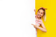 © Марина Демешко - A young caucasian happy smiling pretty blonde woman poins at white advertisement blank board with her finger, demonstrates copy space for text or design on a bright color yellow background. Banner