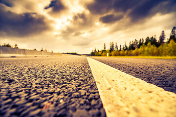 Wall Mural - Autumn on the country road, grim and tense autumn sky over the empty road. View from a wide angle from the level of the dividing line