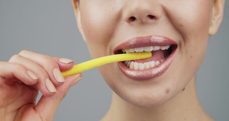 Sticker - Sexy young woman eating sweet marmalade on grey background, closeup