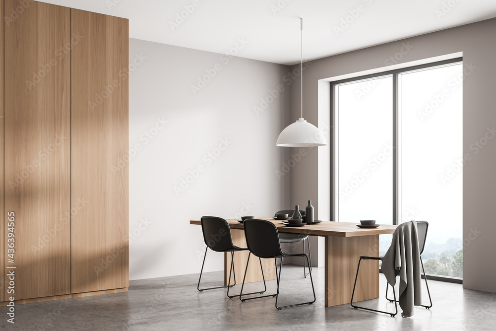 Stylish wood and concrete interior of dining room with design table and four black chairs. Minimalist style of home decor. Panoramic window with view. Empty copy space wall. - obrazy, fototapety, plakaty 