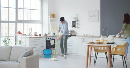 Sticker - Young couple having fun while cleaning kitchen