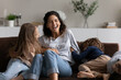 Smiling young Hispanic mom relax in living room play tickle with two little preschooler kids. Happy Latin mother have fun feel playful with game with biracial children at home on family weekend.