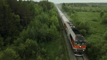 Passenger Train Rides On A Railway In A Beautiful Forest Shooting From The Air. The Drone's Camera Follows The Train From The Air.