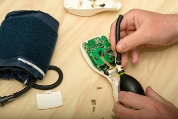 Wall Mural - the master repairs the electronic tonometer inserts a rubber bulb into the body of the tonometer