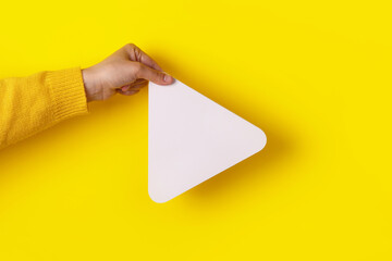 hand holding media player button icon over trendy yellow background