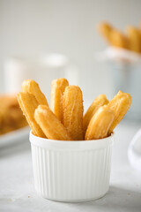 Churros with sugar and cinnamon on a light background. Traditional Spanish street fast food, homemade baking.