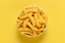 Close Up Of Cheese Potato Puff Snacks Sticks, Popular Ready To Eat Crunchy And Puffed Snacks Sticks  Cheesy Salty Pale-yellow Color Over White Background