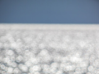Wall Mural - White, blue and grey bokeh effect and purposely blurred view of sea or ocean landscape. Blurry and shiny water and sky background