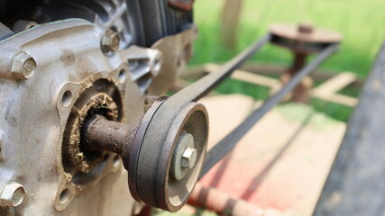 Wall Mural - Close up the belt on the pulley. The metal core of the small engine transmits force through the belt to the blade in front of the walk-behind mower. Selective focus