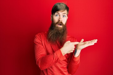 Canvas Print - Redhead man with long beard pointing open palm with finger clueless and confused expression. doubt concept.