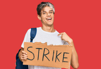 Wall Mural - Young hispanic man holding strike banner cardboard pointing finger to one self smiling happy and proud