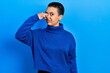 © Krakenimages.com - Beautiful hispanic woman with short hair wearing turtleneck sweater smelling something stinky and disgusting, intolerable smell, holding breath with fingers on nose. bad smell