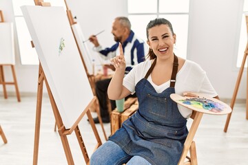 Poster - Young artist woman at art studio surprised with an idea or question pointing finger with happy face, number one