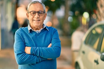Wall Mural - senior grey-haired man with arms crossed smiling happy standing at the city.